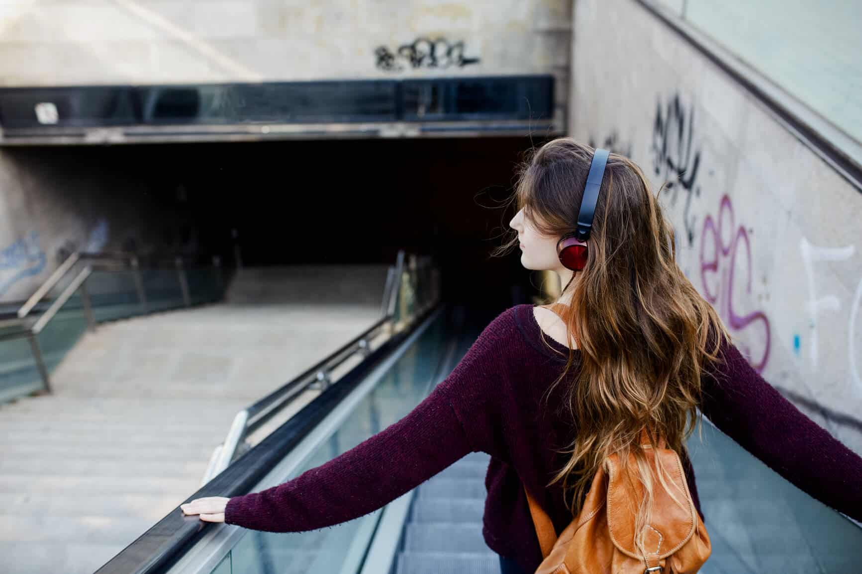 teenage girl outside walking down stairs with headphones on