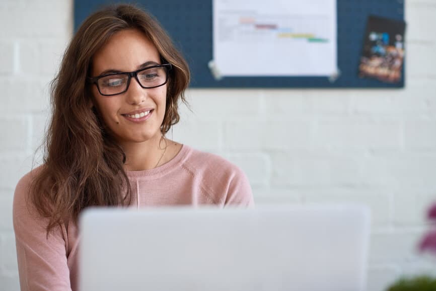 woman sitting on couch on laptop with headphones in for online therapy